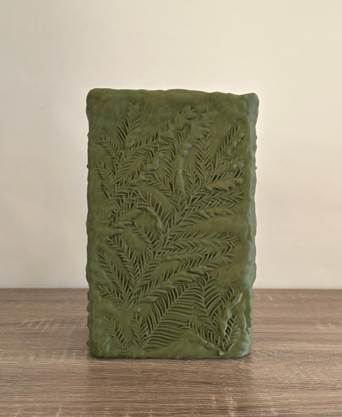 Vela decorativa verde com padrão de folhas e textura gravada