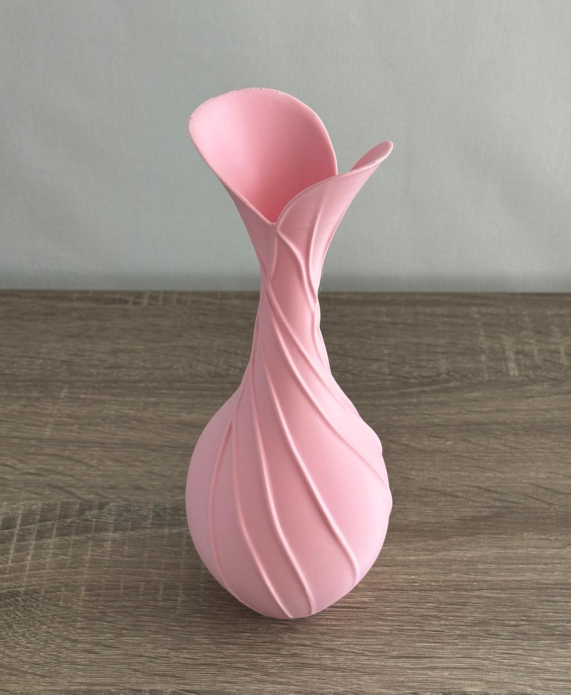 Vaso decorativo cor-de-rosa cerâmico com textura ondulada sobre madeira