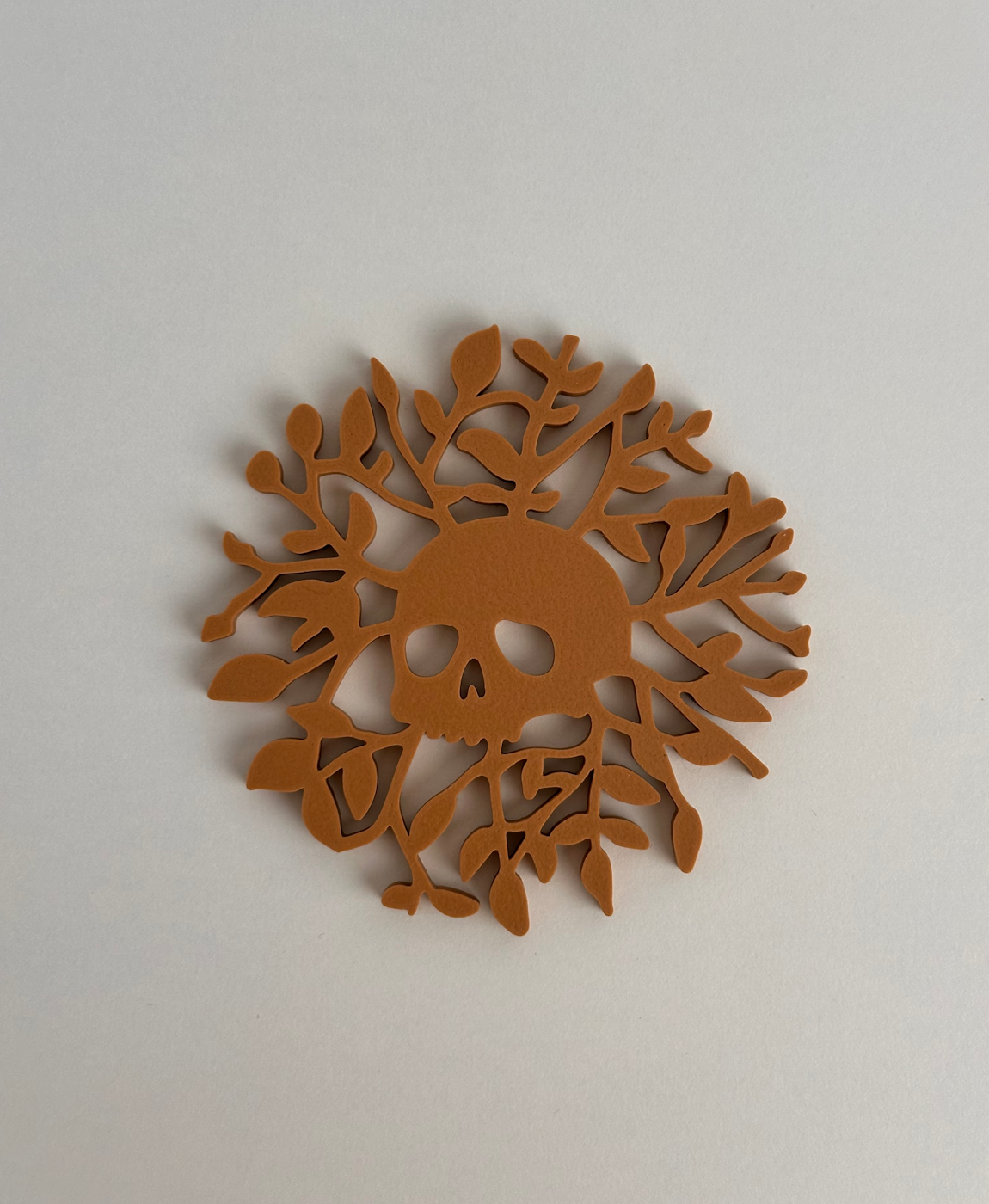 Elemento decorativo castanho com caveira e ramos