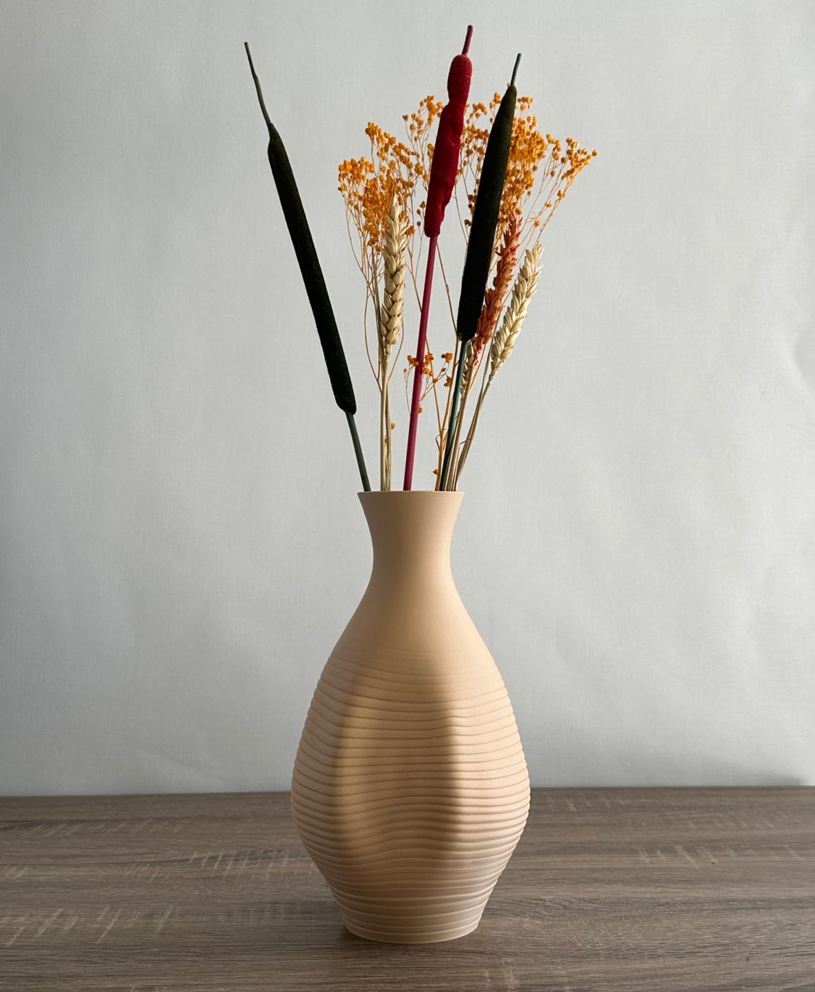 Vaso cerâmico bege com flores secas em fundo branco