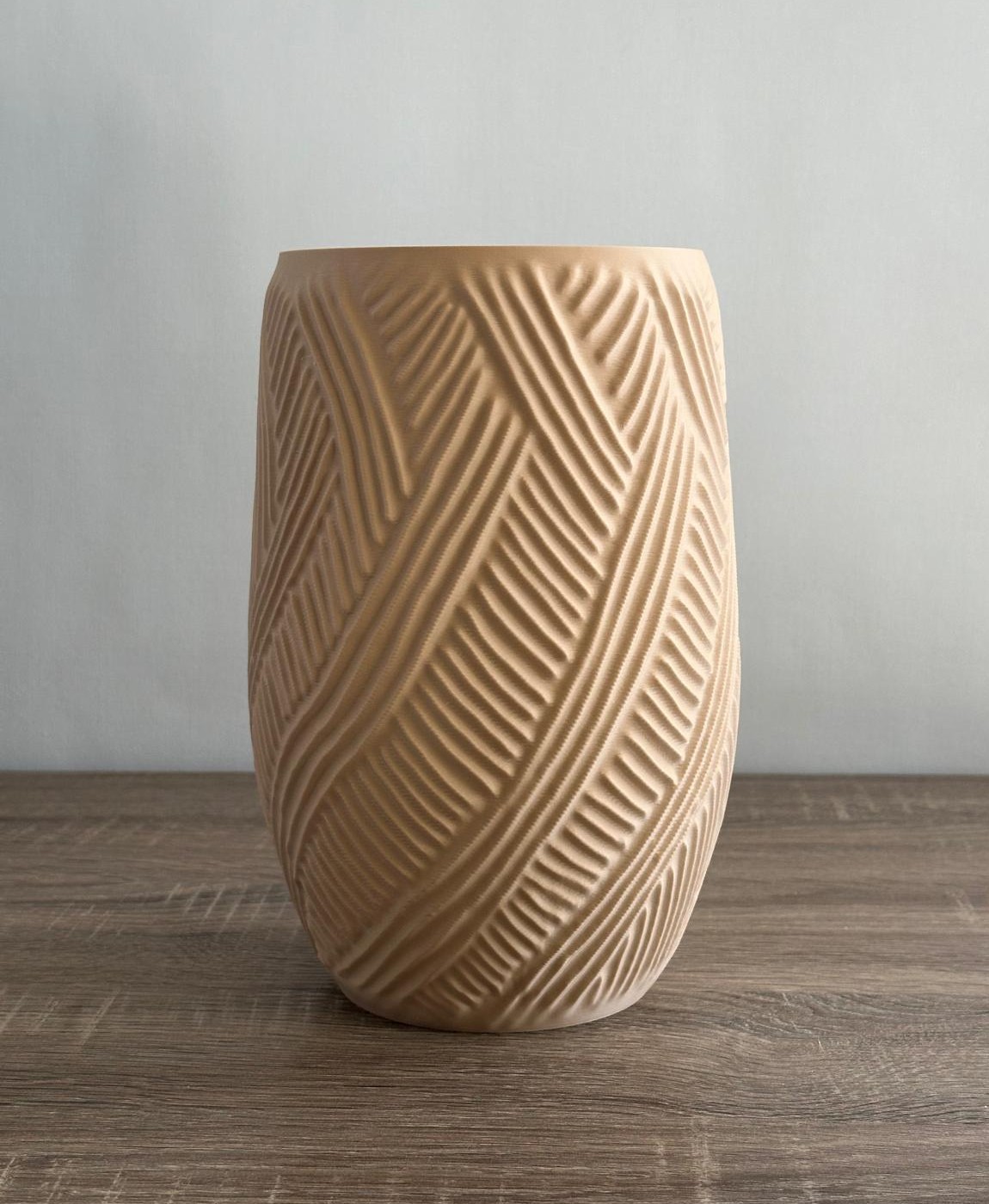 Vaso de cerâmica bege com padrão geométrico em mesa de madeira