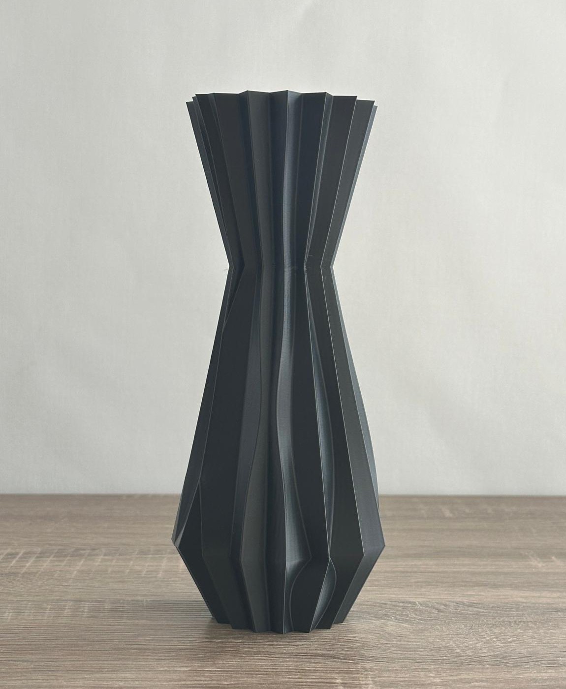 Vaso preto geométrico sobre superfície de madeira clara