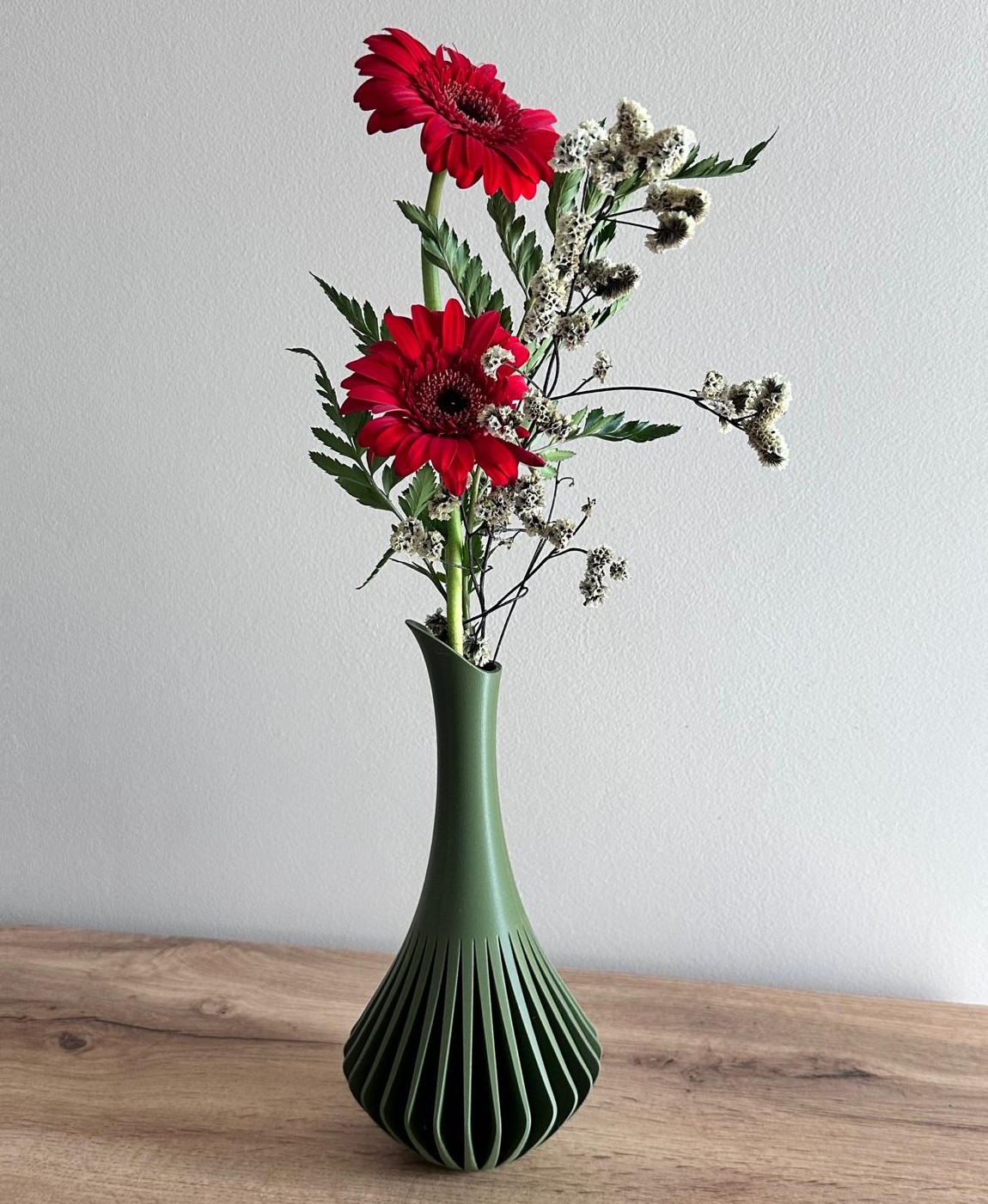 Vaso verde escuro com flores vermelhas e brancas