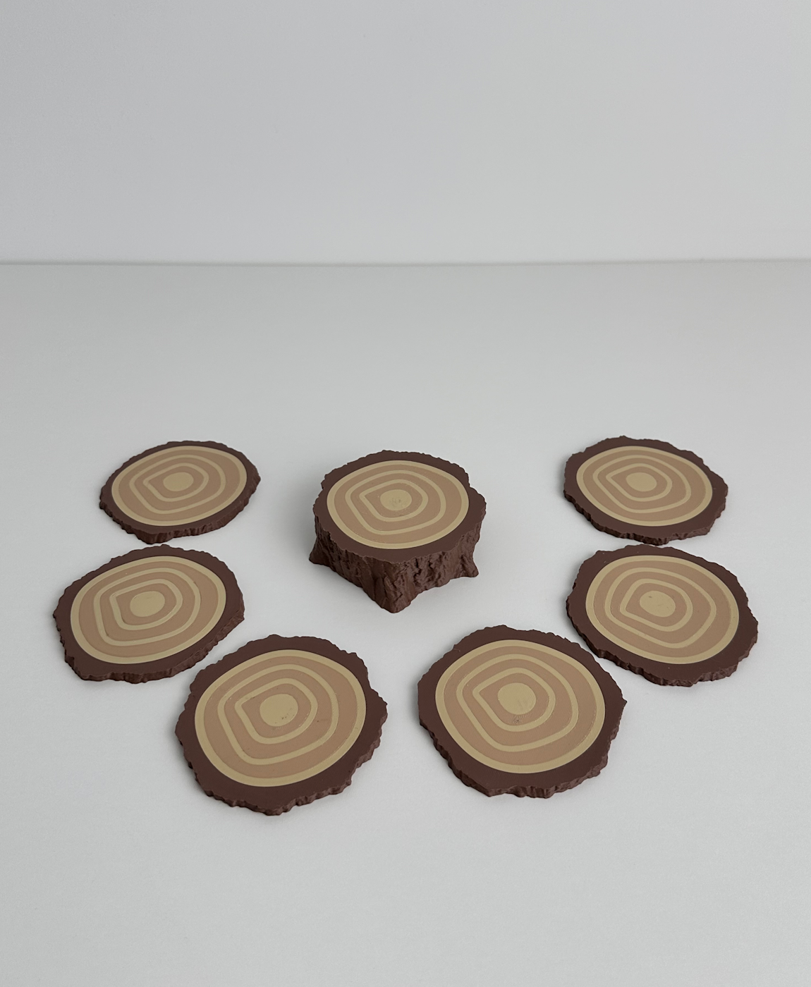 Descansos de copos em forma de tronco de árvore em diferentes tons de castanho.