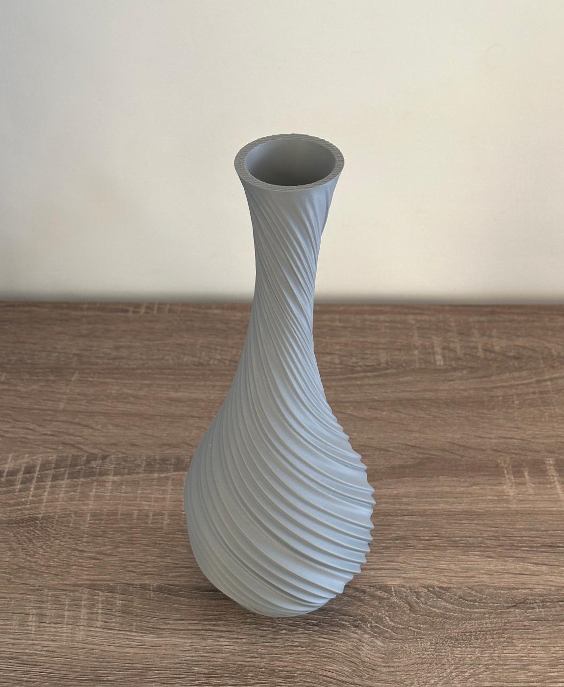 Vaso cinzento claro texturizado espiral em mesa de madeira