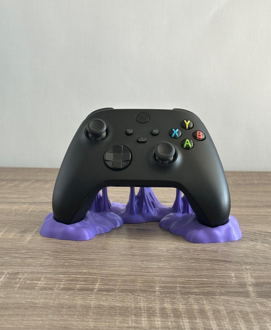 Comando de videojogo preto numa base roxa em superfície de madeira clara