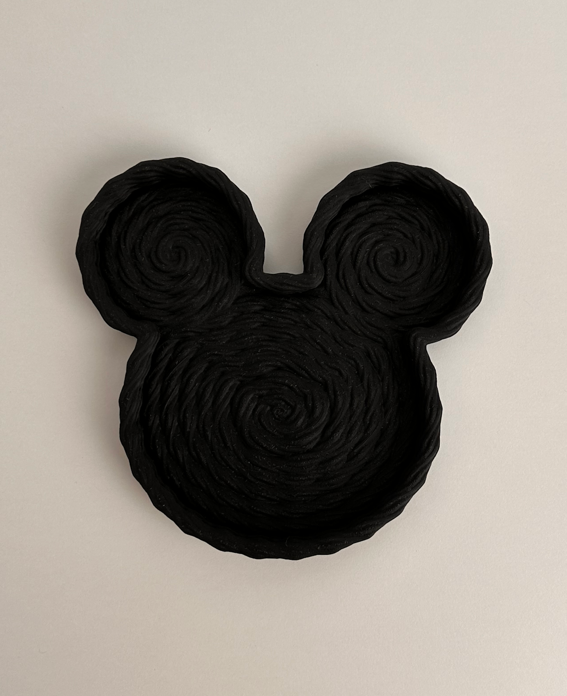 Prato preto em forma do rosto do Mickey Mouse com textura enrolada.