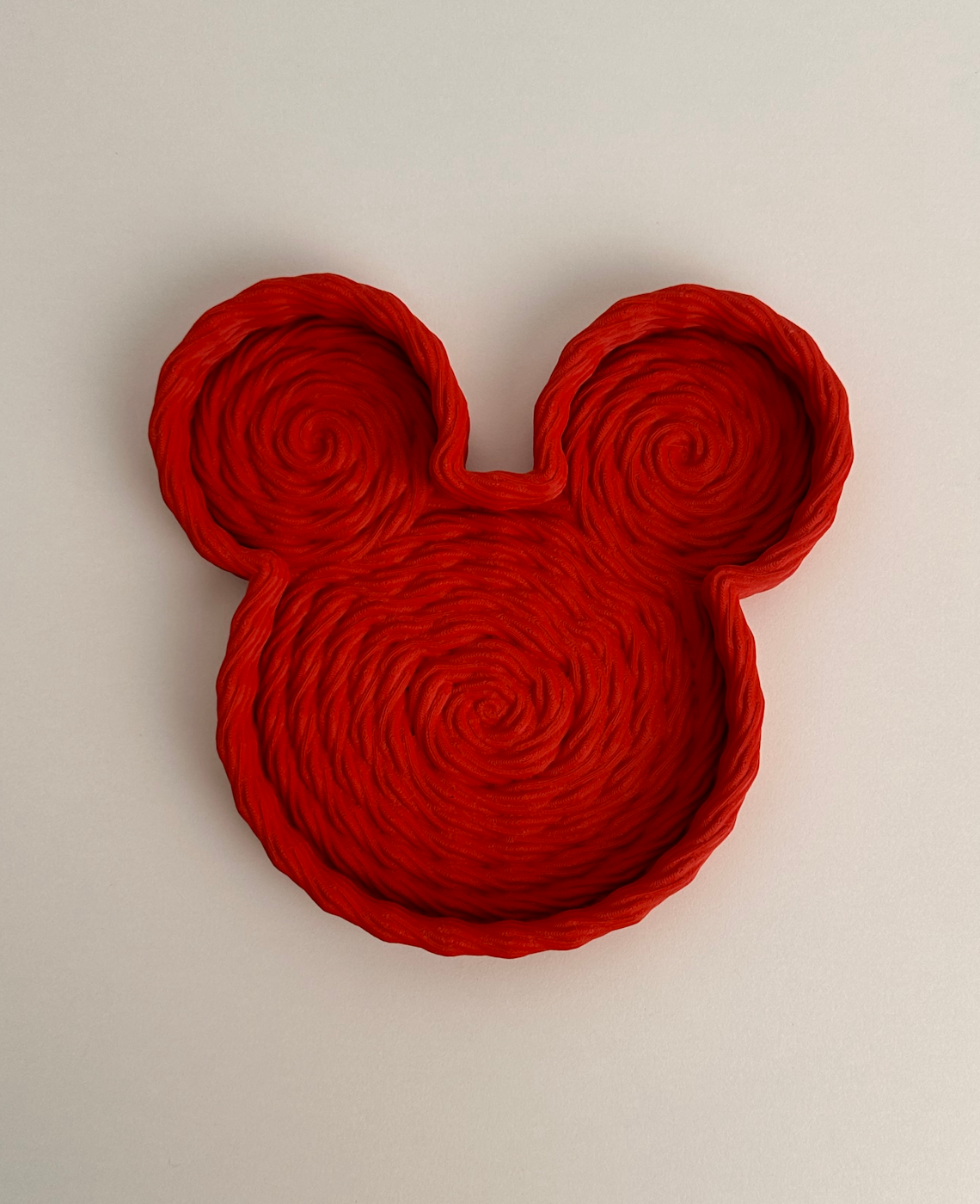 Prato vermelho em forma da cabeça do Mickey Mouse com padrão trançado espiral.