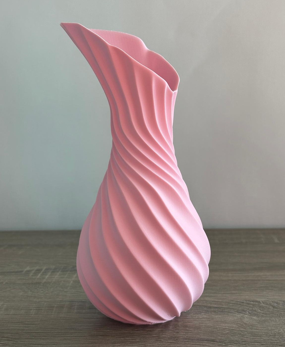 Vaso decorativo rosa com textura ondulada em fundo cinzento