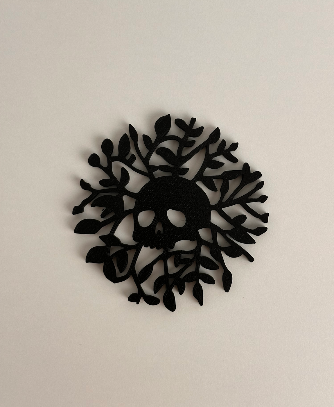 Adorno preto em forma de caveira com ramos e folhas sobre fundo branco