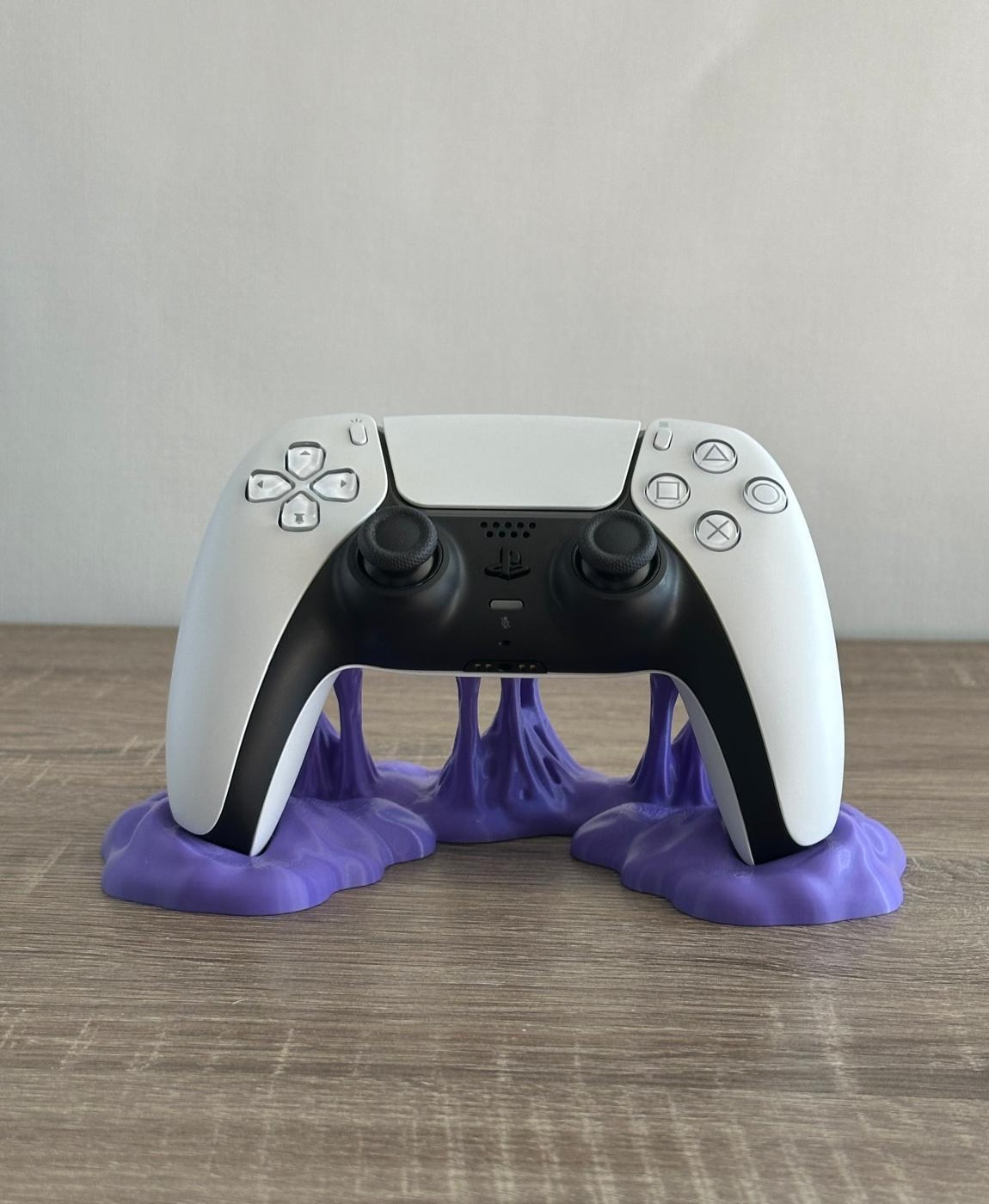 Comando de videojogo branco e preto sobre base roxa em mesa de madeira.