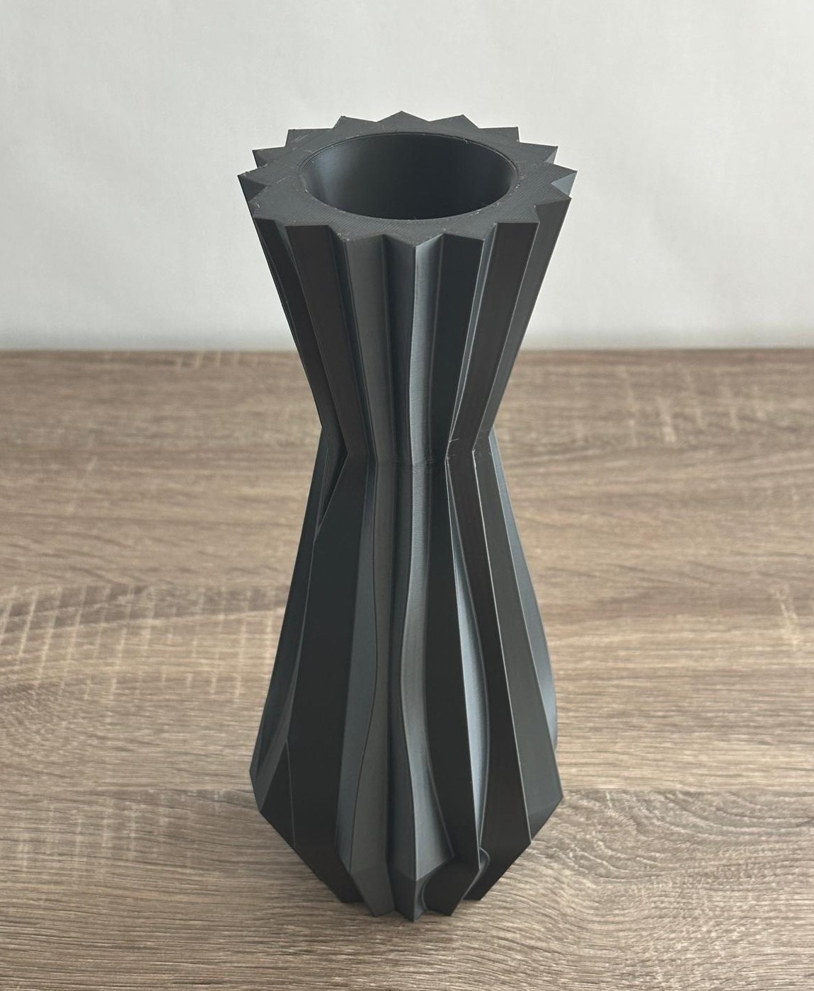 Vaso preto com design geométrico sobre mesa de madeira