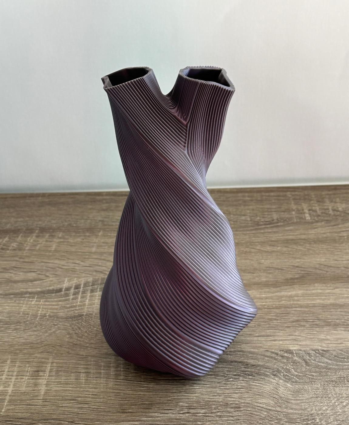Vaso torcido roxo com textura de linhas sobre mesa de madeira