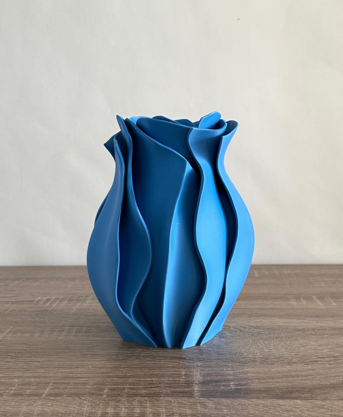 Vaso decorativo azul com design ondulado em madeira clara