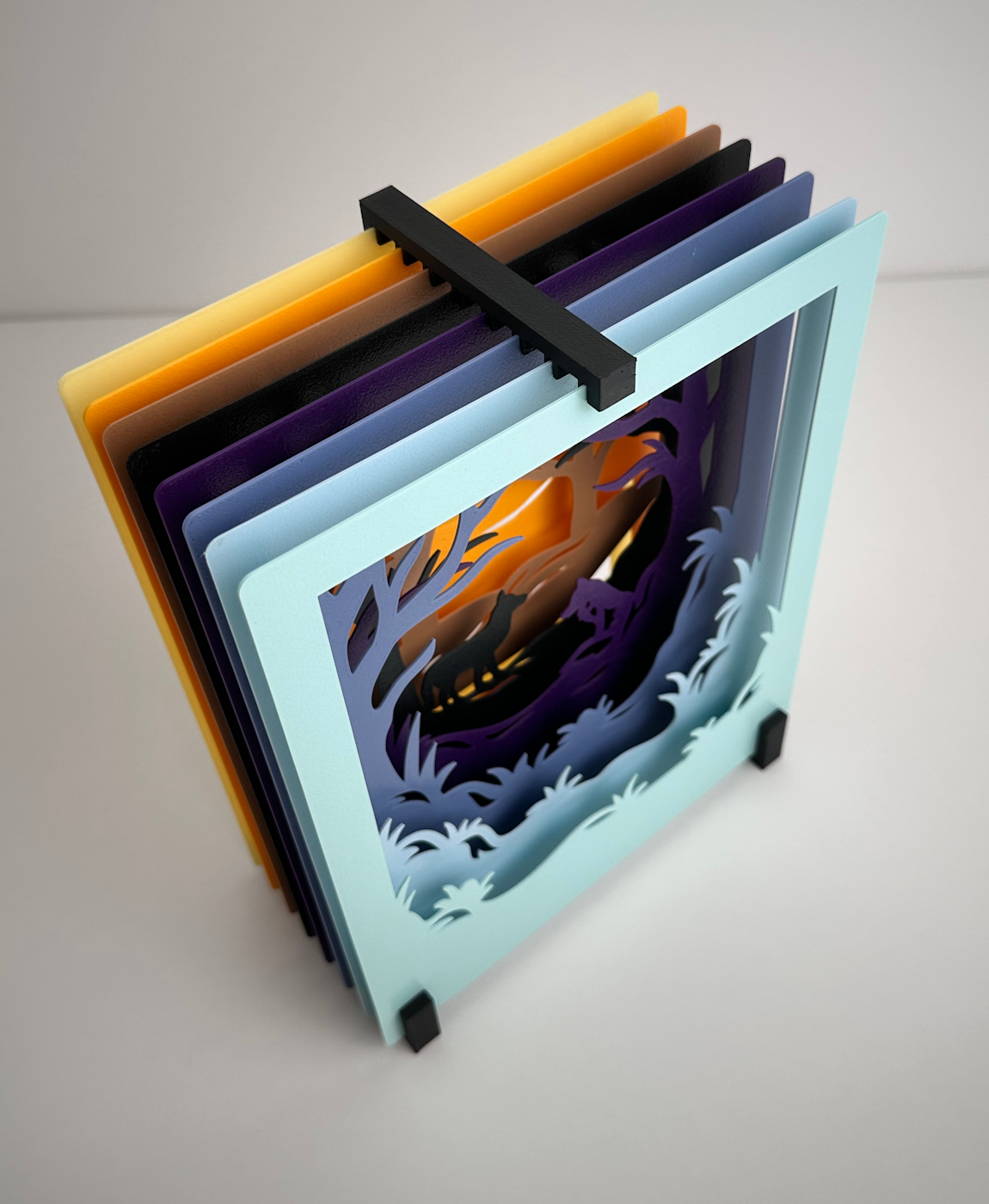 Decoração de camadas de cartão colorido formando uma cena de floresta com animais