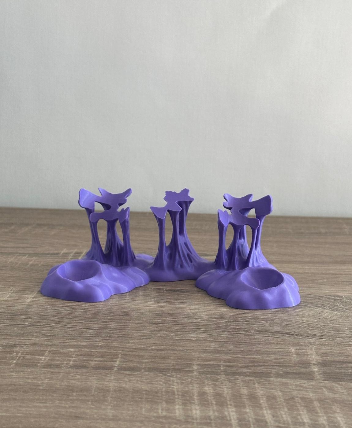 Três suportes pequenos roxos abstratos sobre mesa de madeira