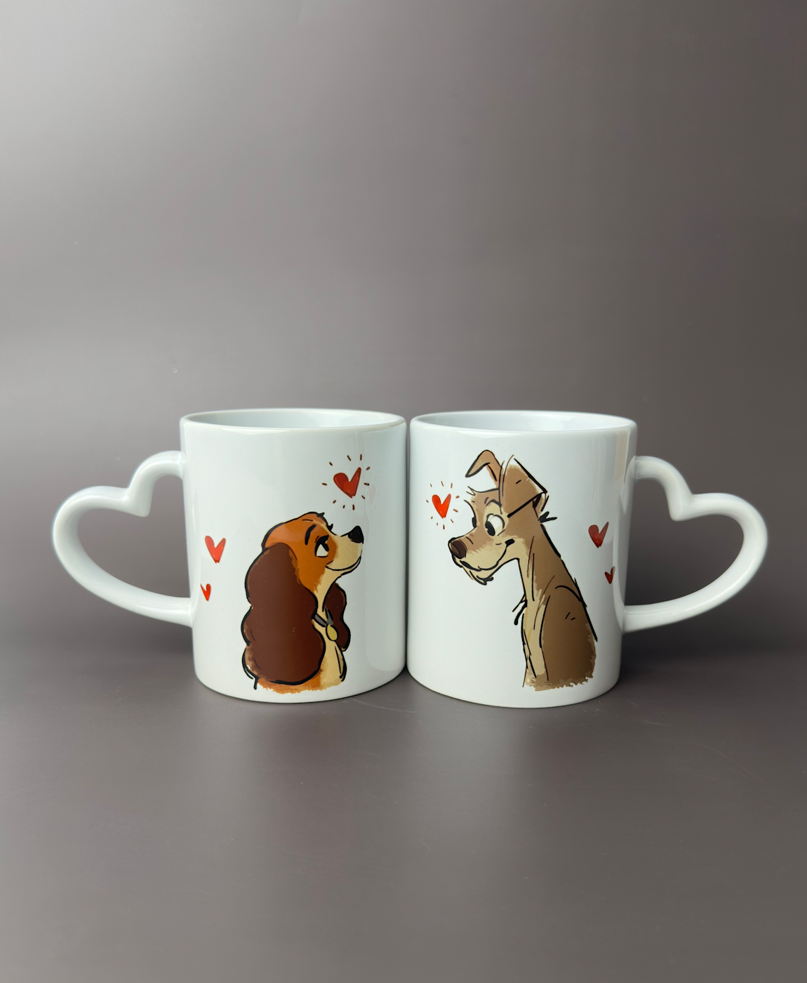 Duas canecas brancas com pegas em forma de coração e ilustrações de cães com corações vermelhos.