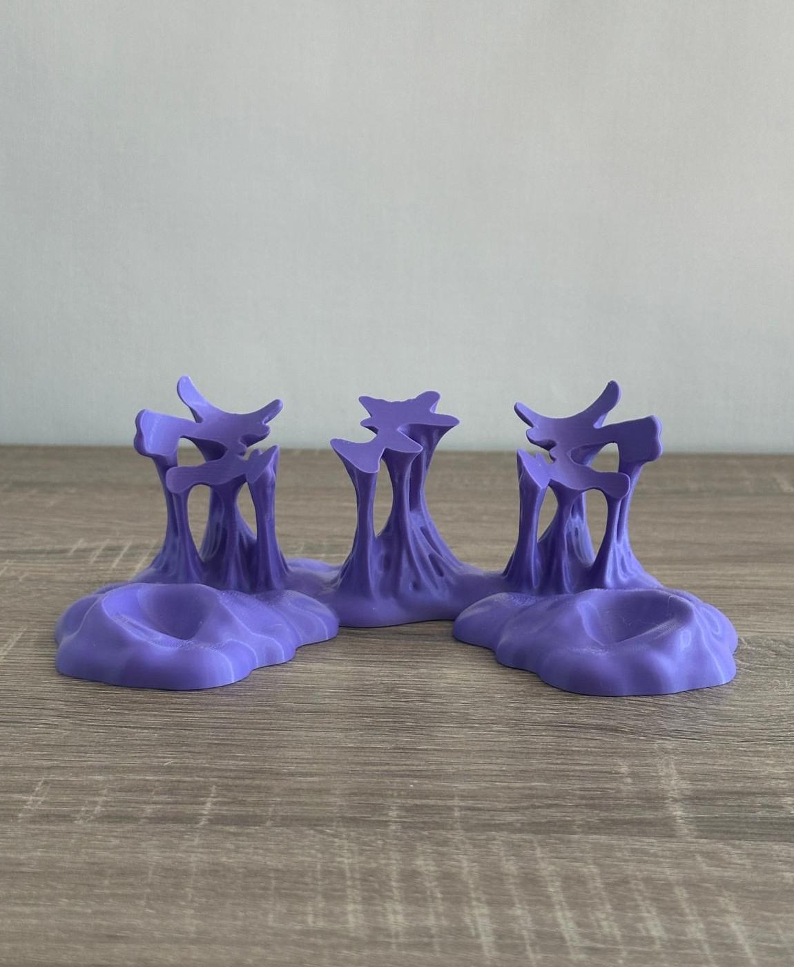 Três suportes plásticos lavanda com formas abstratas em superfície de madeira