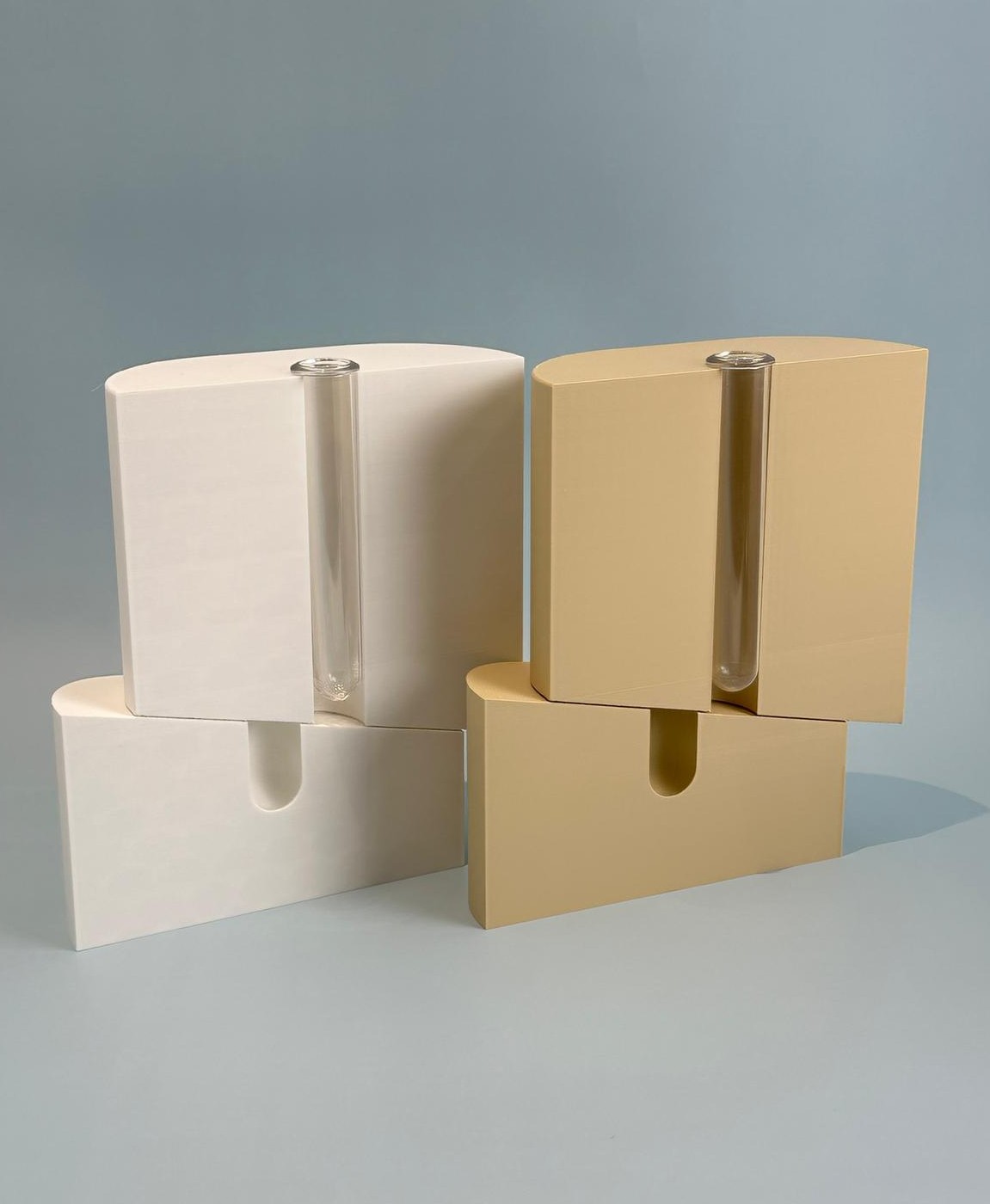 Quatro objetos de design minimalista com estrutura metálica transparente, duas brancos e dois beges