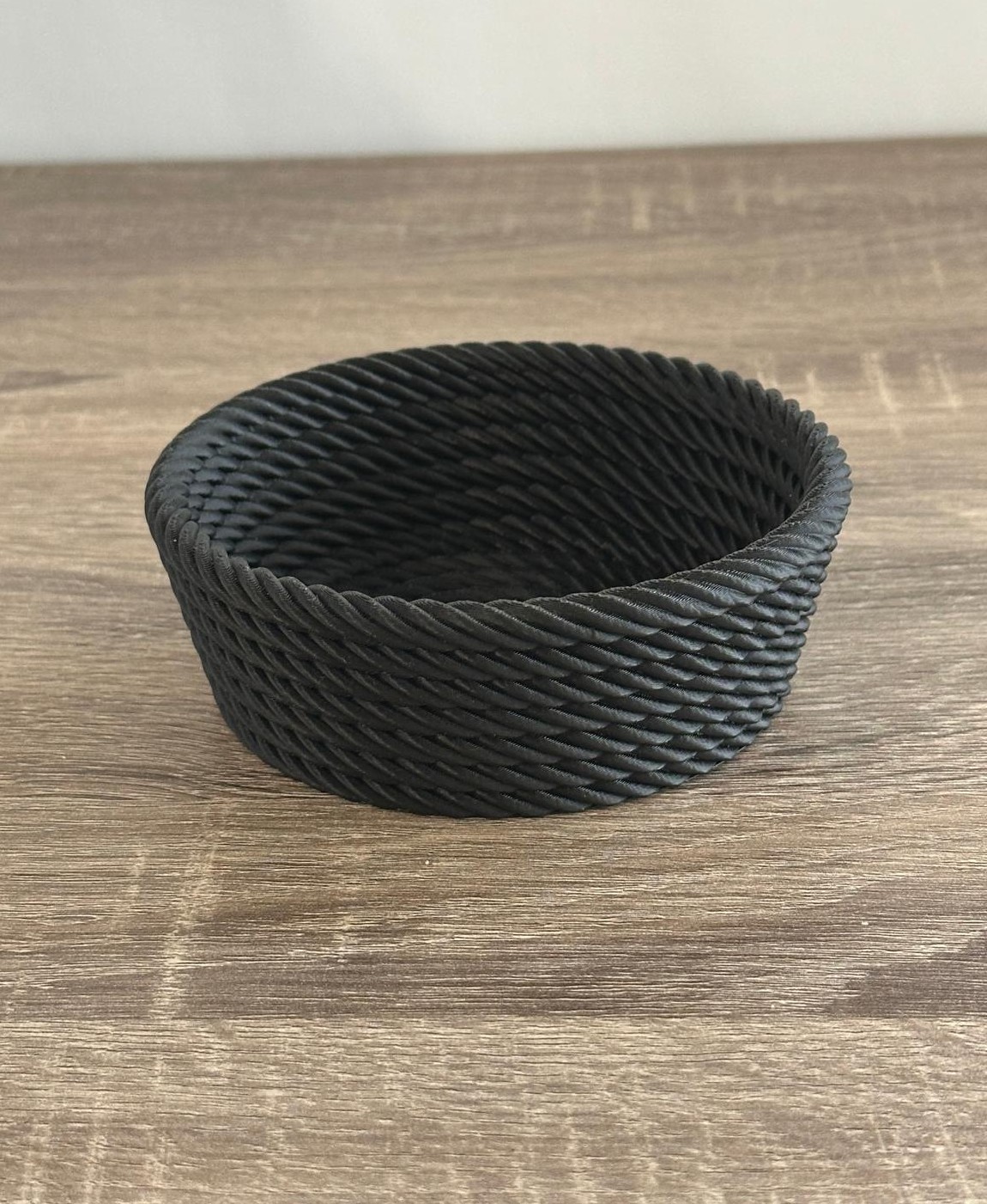 Cesta redonda preta com textura de corda trançada