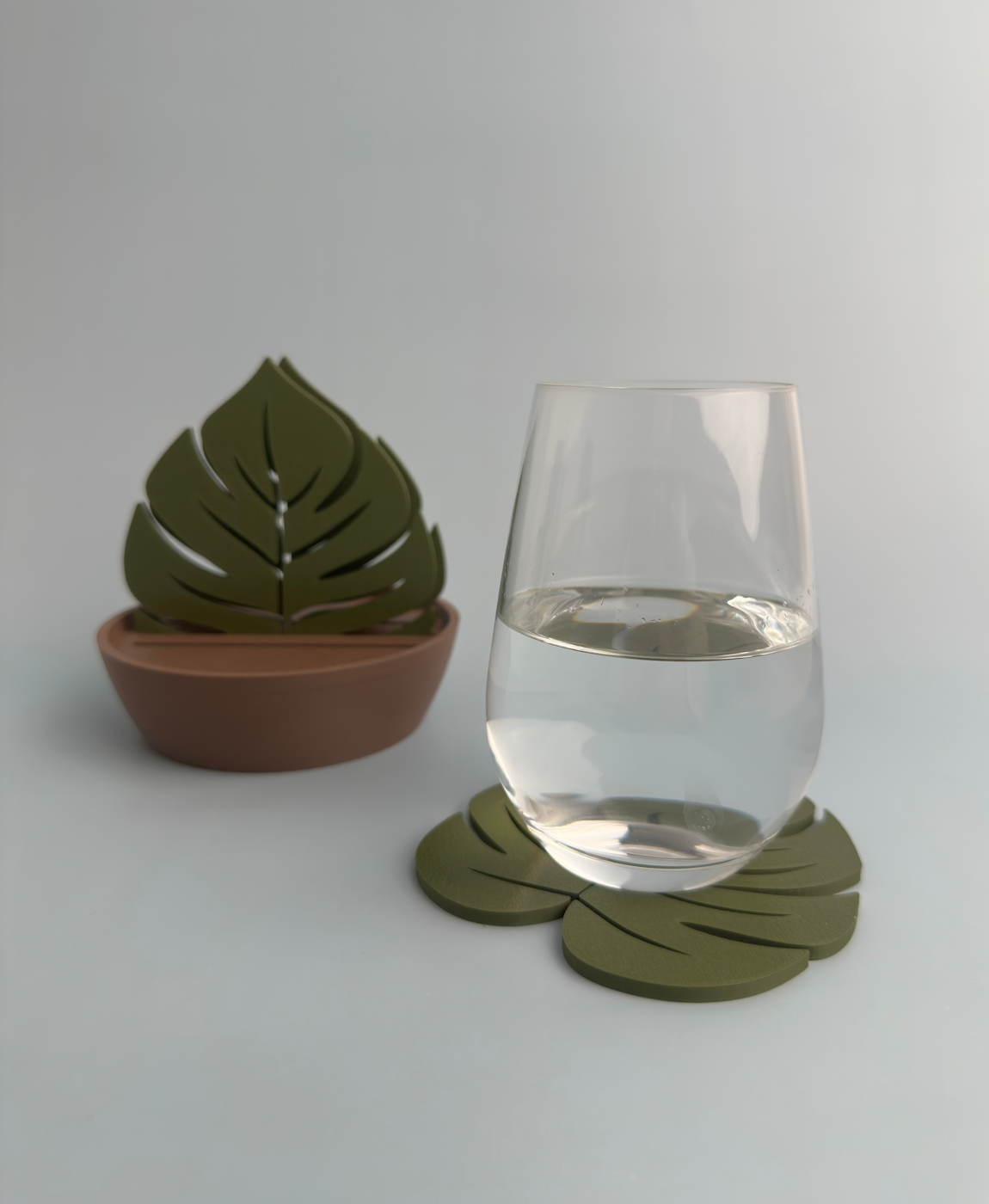 Apoio para copos verdes em forma de folha com copo de água e suporte castanho