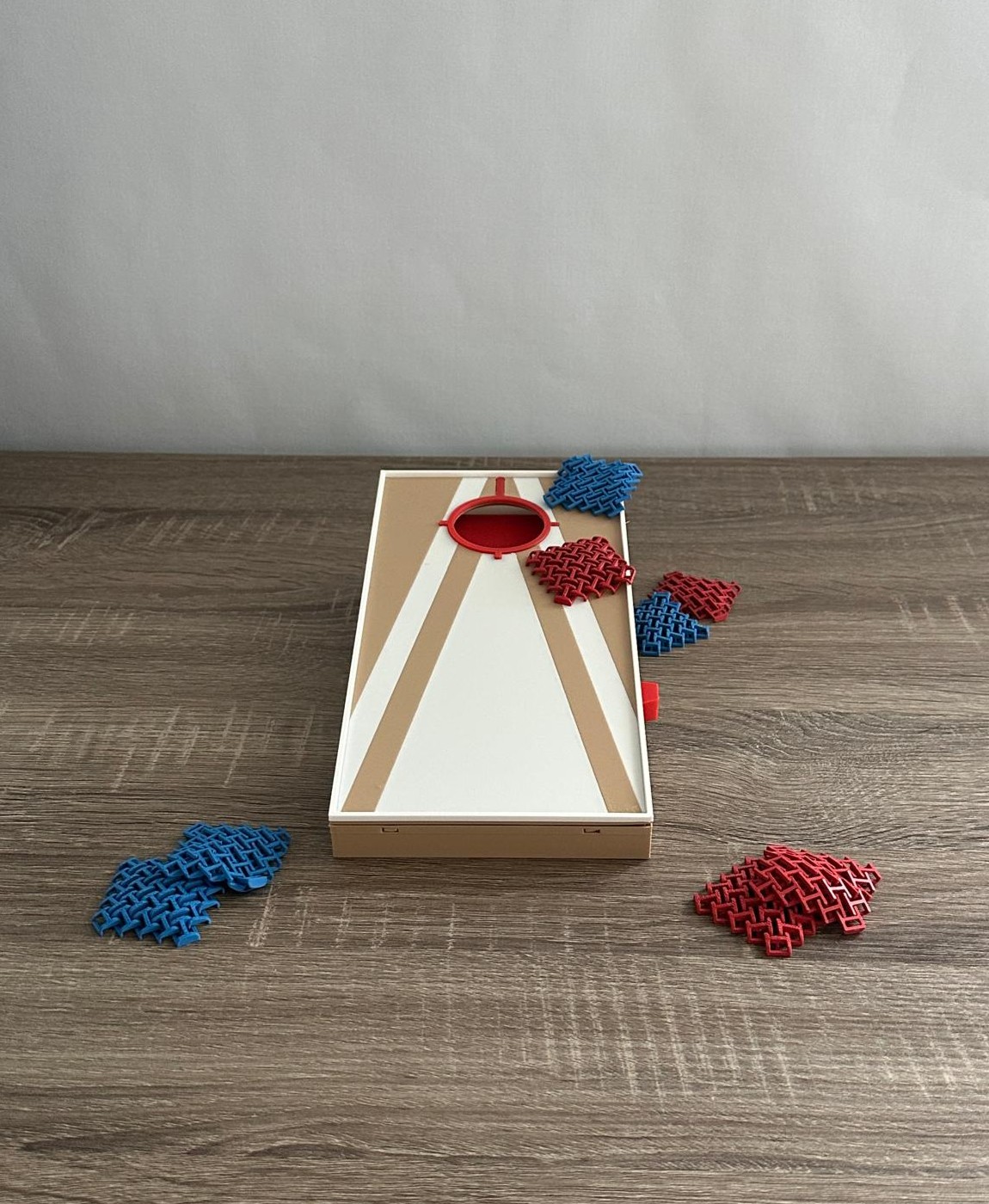 Jogo de tabuleiro retangular branco e bege com peças azuis e vermelhas sobre uma mesa de madeira.