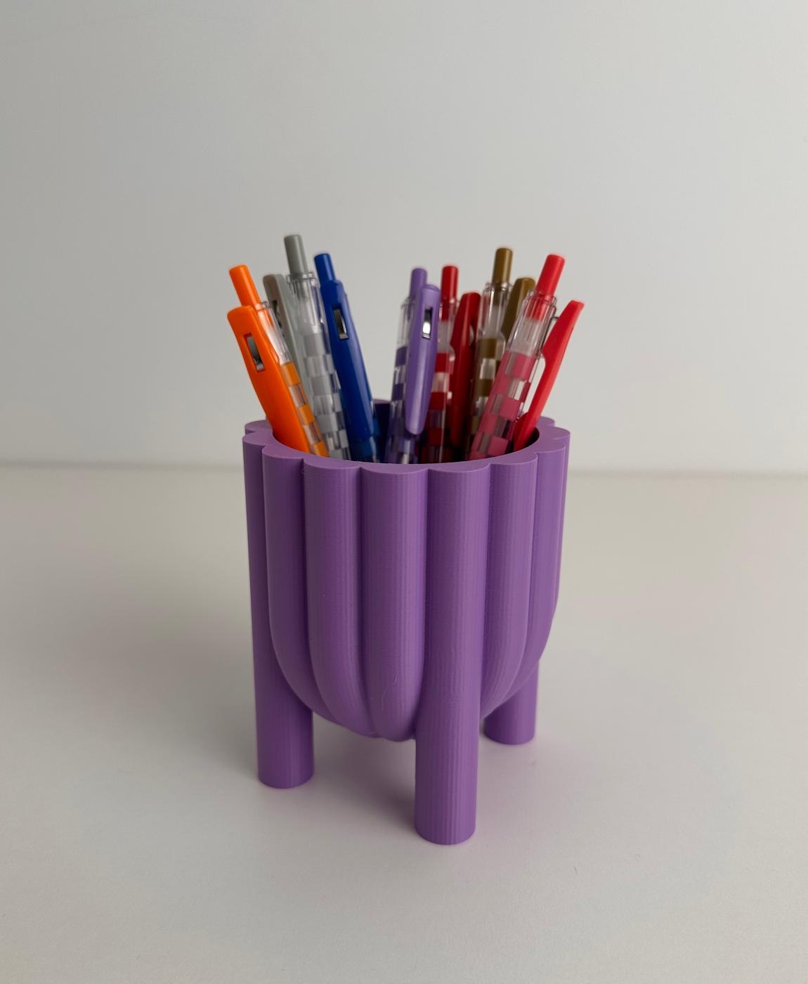 Suporte roxo para canetas com várias canetas coloridas