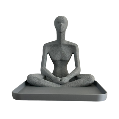 Estátua cinzenta de figura humana sentada em posição de lótus numa base rectangular cinzenta