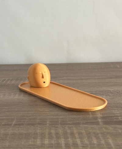 Tabuleiro castanho claro com peça esférica decorada com rosto sorridente