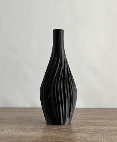 Vaso decorativo preto com textura ondulada em superfície de madeira clara