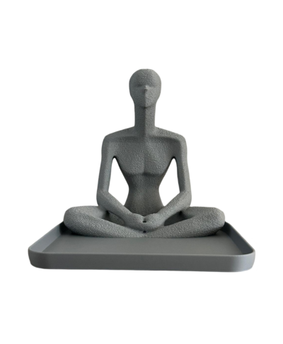 Estátua cinzenta de figura humana sentada em posição de lótus numa base rectangular cinzenta