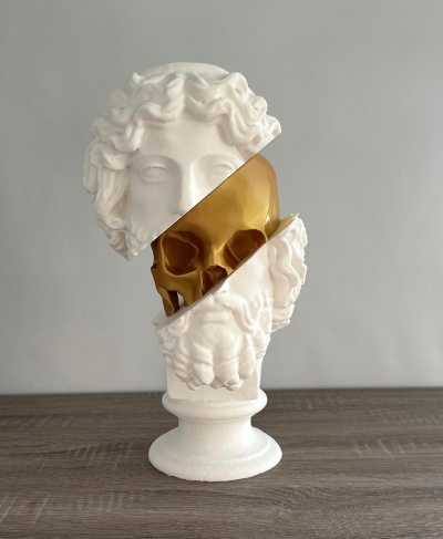 Escultura branca com busto clássico e crânio dourado visível no meio