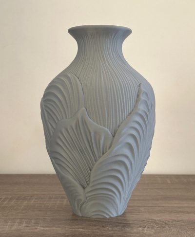 Vaso cinzento texturizado com padrão de folhas em superfície de madeira clara