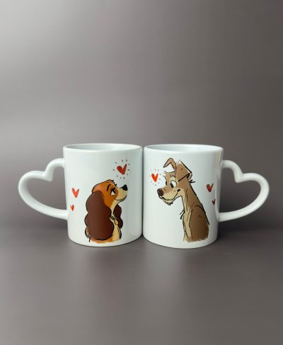 Duas canecas brancas com pegas em forma de coração e ilustrações de cães com corações vermelhos.