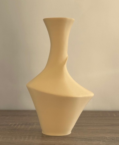 Vaso decorativo cerâmico bege com design assimétrico sobre uma mesa de madeira