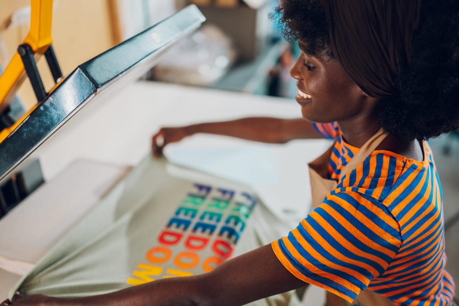 Pessoa a usar máquina de impressão em tecido com texto colorido 'FREEDOM PIECE OF'