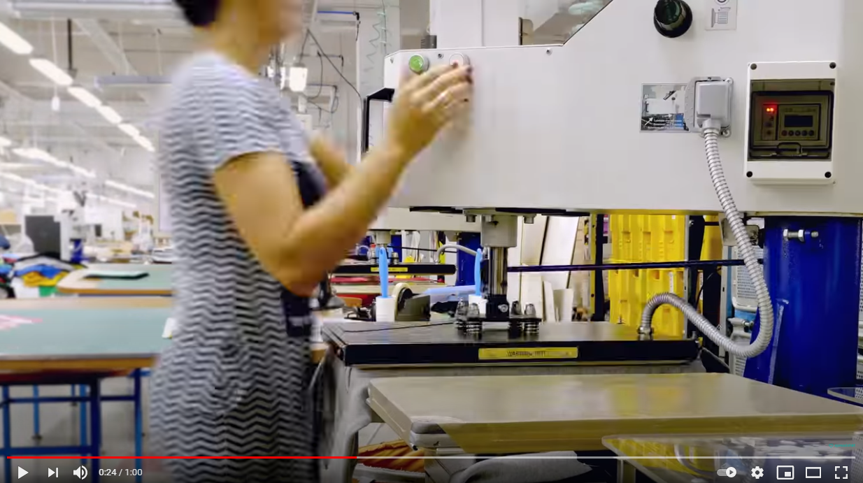 Mulher com vestido às riscas opera máquina industrial em fábrica