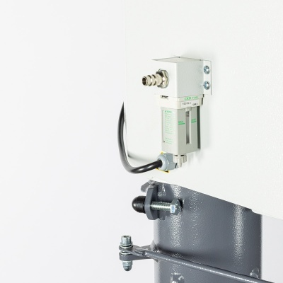 Componente industrial branco com ligação metálica e cabo, montado numa superfície branca e suporte cinzento.