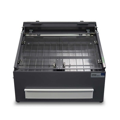 Equipamento industrial cinzento com tampa transparente e componente metálico.