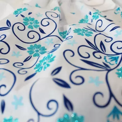 Tecido branco com padrão floral azul e detalhes em glitter turquesa