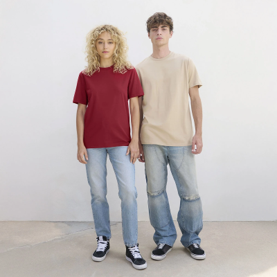Modelos vestem t-shirts vermelha e bege com jeans claros e ténis pretos