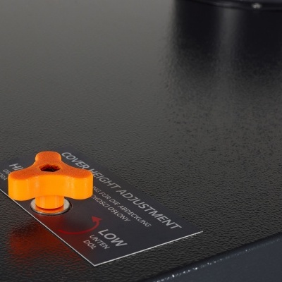 Peça metálica preta com parafuso laranja e etiqueta de ajuste