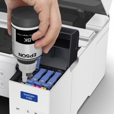 Frasco de tinta preta Epson sendo inserido em impressora Epson branca com tanques de tinta colorida visíveis