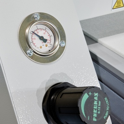 Manómetro analógico e botão preto com inscrições verdes em superfície branca