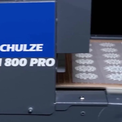 Máquina Schulze KN 800 PRO em funcionamento para fixar impressões em t-shirts.