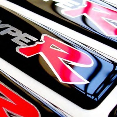 Placa com logotipo 'TYPE R' em preto, cinza e vermelho num automóvel