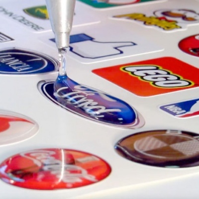 Adesivos coloridos brilhantes com resina sendo aplicada manualmente