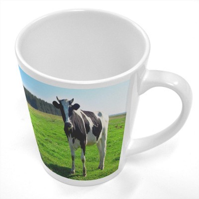 Caneca branca com imagem de vaca num campo verde