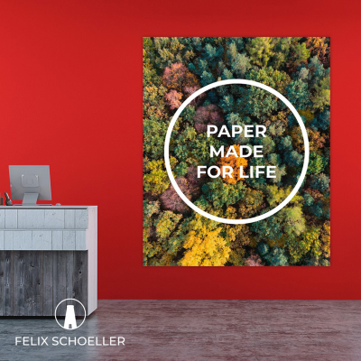 Póster colorido de floresta com texto 'PAPER MADE FOR LIFE' numa parede vermelha atrás de balcão