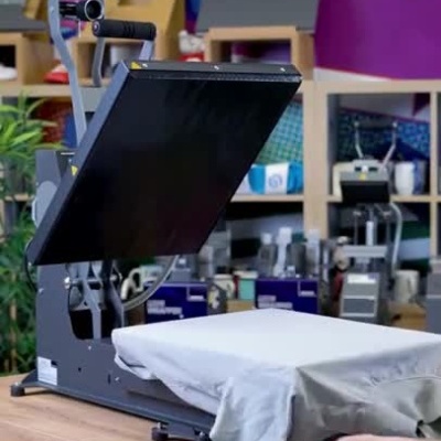 Prensa térmica a estampar uma t-shirt branca numa oficina